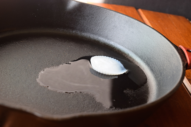 frozen coconut oil cube melting in frying pan skillet
