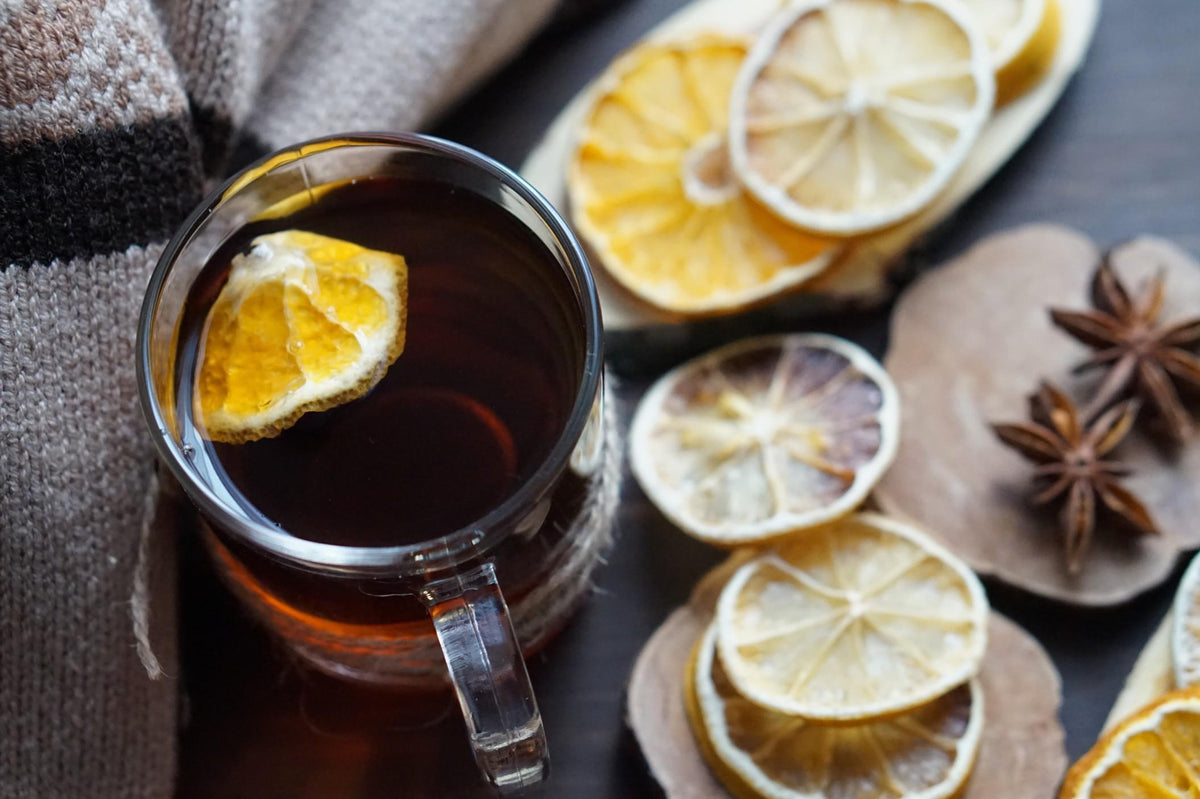 a mug of tea with lemon slices and herbs