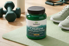 Swanson creatine monohydrate powder jar on a green exercise mat with dumbbells and sneakers