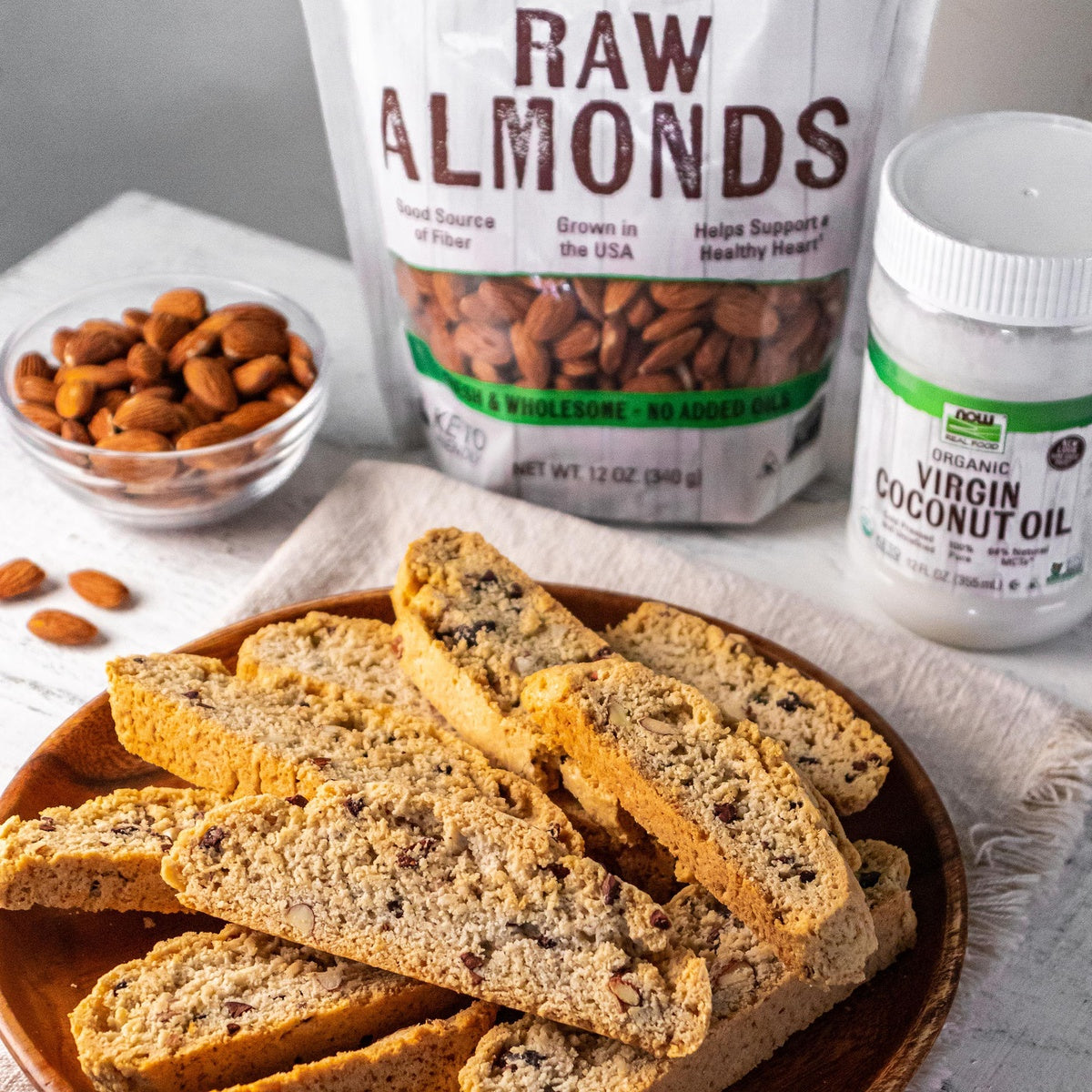 NWF927 | Biscotti slices served with raw almonds and virgin coconut oil in the background