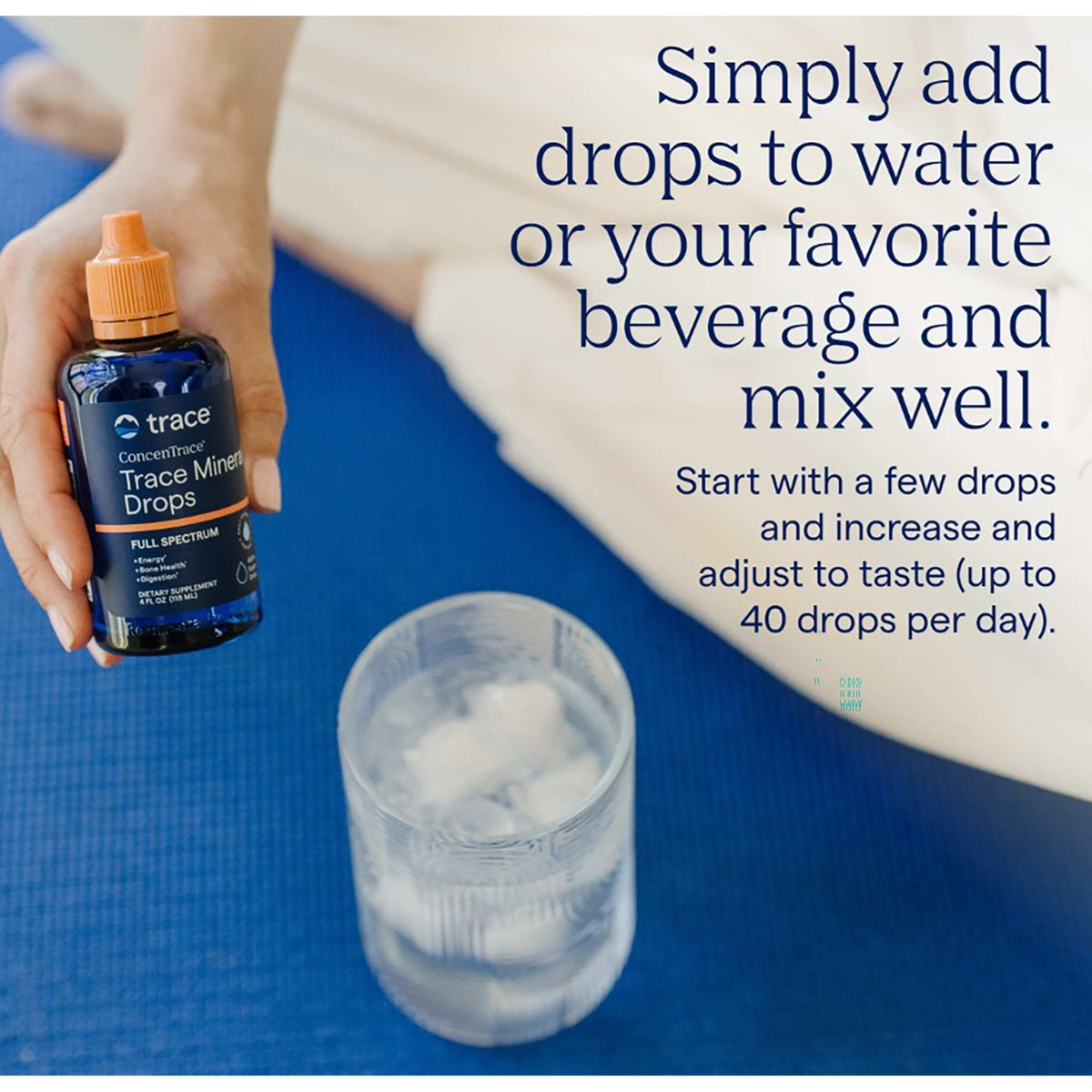 TM034 | Hand holding Trace ConcenTrace mineral drops beside a glass of water with usage instructions