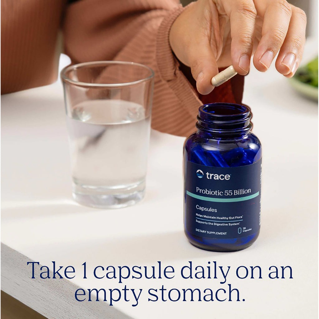TM081 | Woman taking a probiotic capsule beside a glass of water and Trace Probiotic 55 Billion bottle - Thumbnail