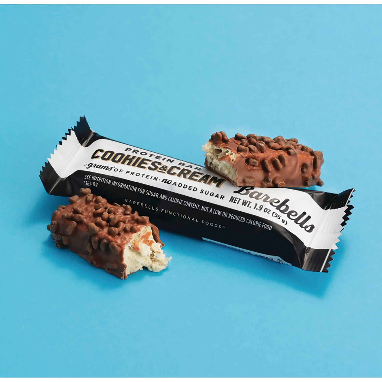 BAE003 | Back view of Cookies & Cream protein bar wrapper with two chocolate-covered broken bars on a blue background