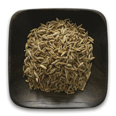 FNP078 | pile of light brown cumin seeds on a square dark wooden dish