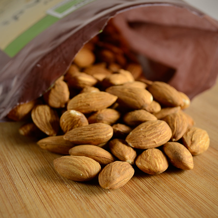 NWF927 | raw almonds spilling from open brown bag on wooden surface - Thumbnail