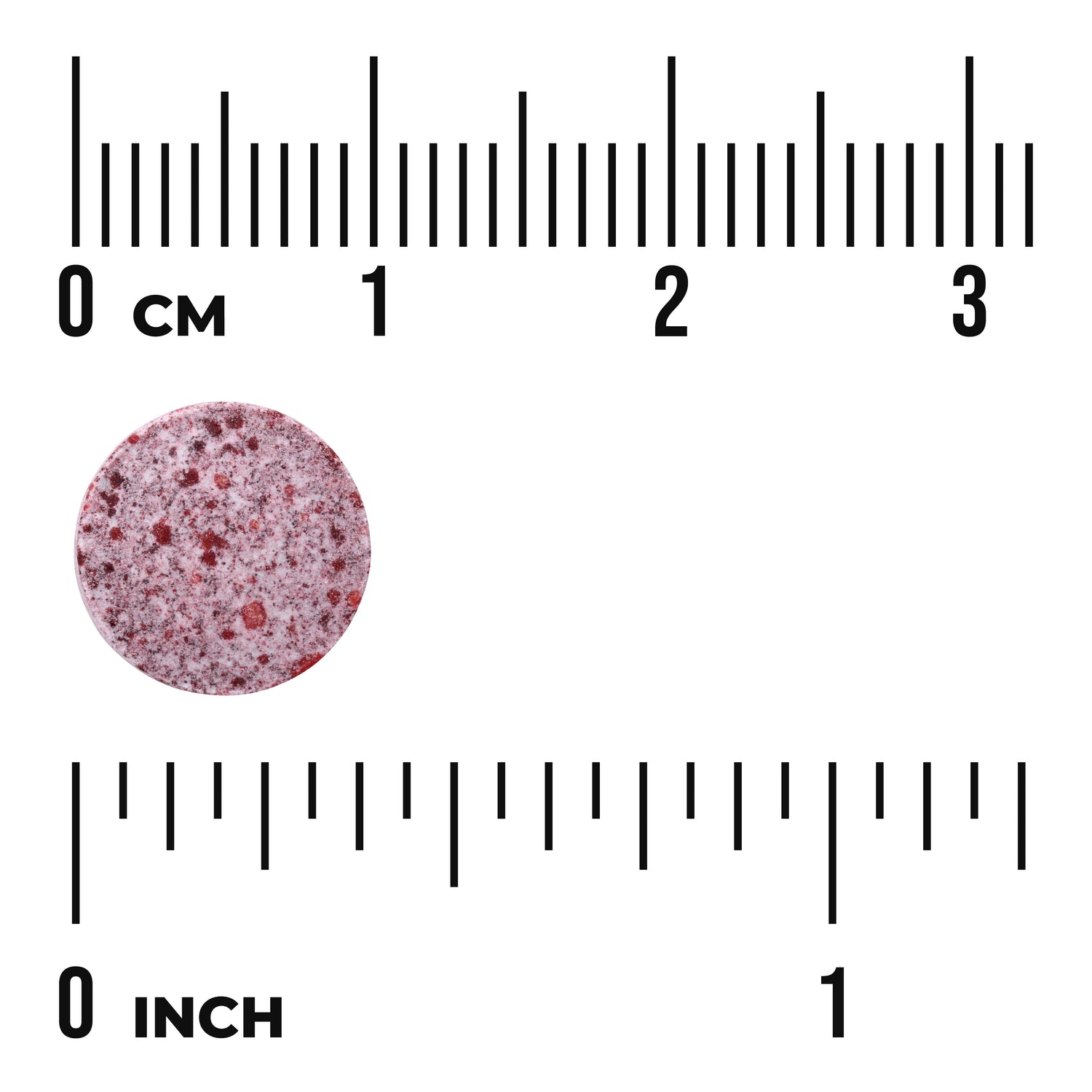 SWU783 | Round speckled red tablet next to centimeter and inch rulers, about 1 cm diameter