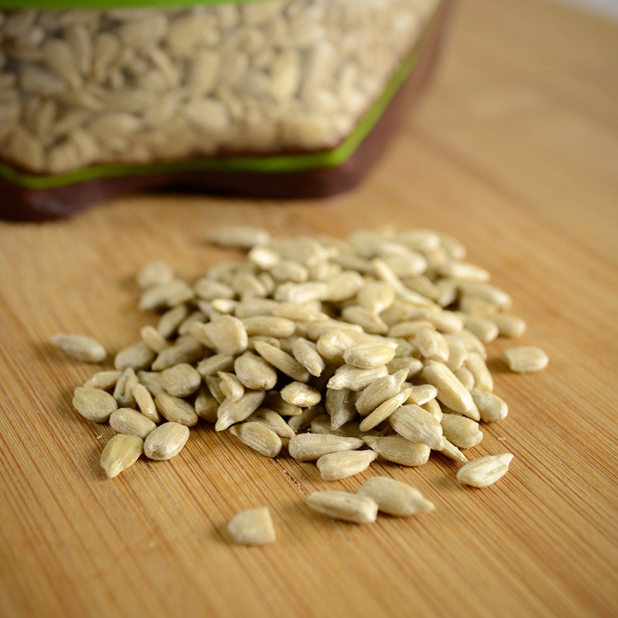 NWF1159 | hulled sunflower seeds spilled on a wooden cutting board with a resealable bag blurred in background - Thumbnail