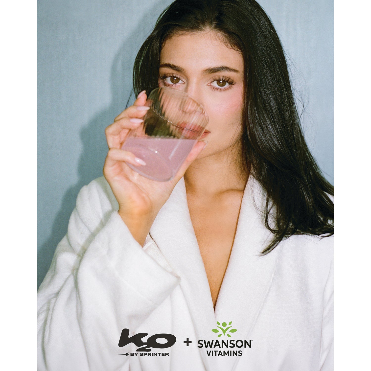 KTO004 | Woman in a white robe sipping a pink drink with KO by Sprinter and Swanson Vitamins logos