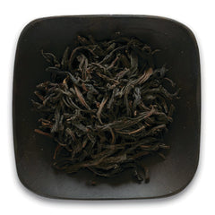 FNP085 | Top-down view of loose dried black tea leaves in a square dark ceramic dish