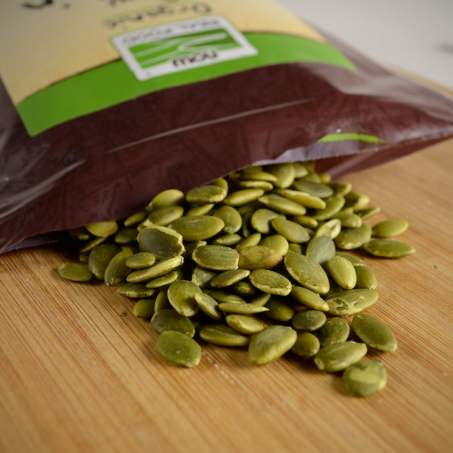 NWF1157 | pumpkin seeds spilling from opened bag onto a wooden cutting board - Thumbnail