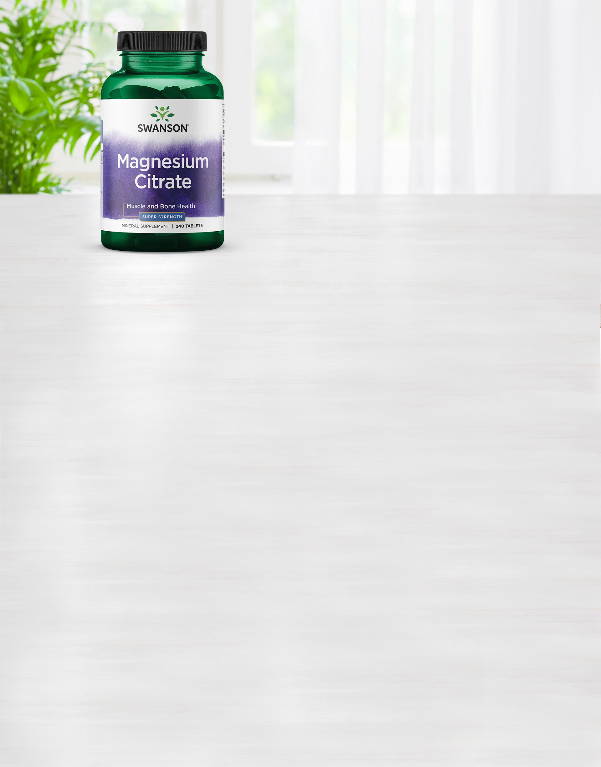 Swanson Magnesium Citrate supplement bottle on a white surface with a blurred green plant in the background