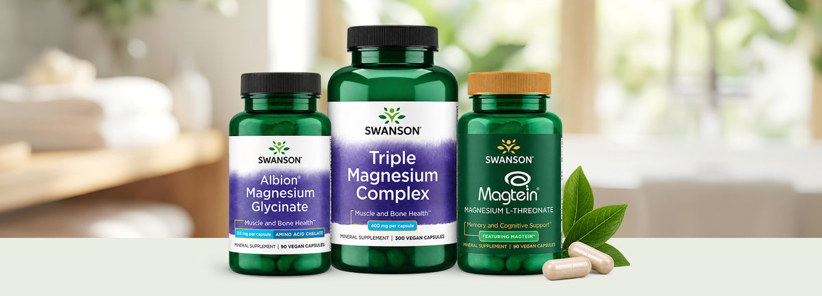 Three Swanson vitamin bottles of Albion Magnesium Glycinate, Triple Magnesium Complex and Magtein with two pill capsules and leaves.