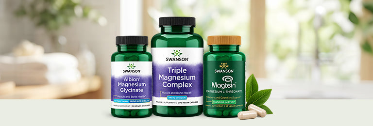 Three Swanson vitamin bottles of Albion Magnesium Glycinate, Triple Magnesium Complex and Magtein with two pill capsules and leaves.