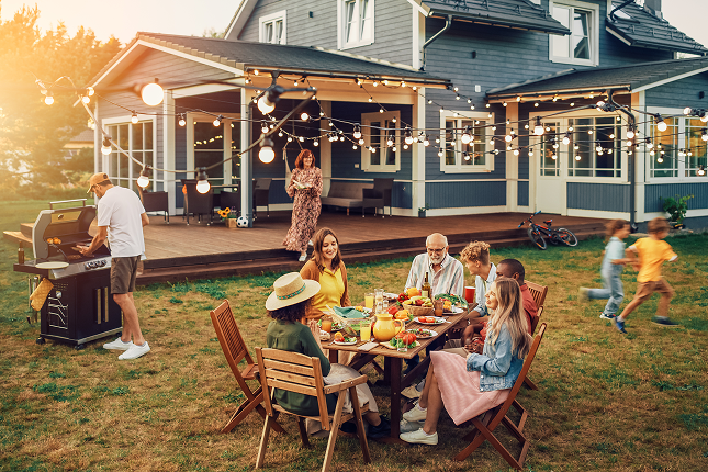 Family gathering on a patio with string lights and a barbecue grill.