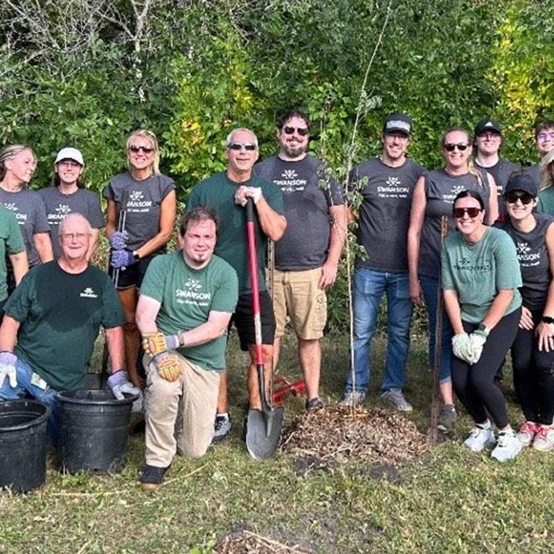 Group of men and women smiling at the camera after doing landscaping work at a park