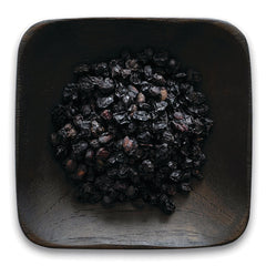 FNP380 | pile of dried dark berries in a square wooden dish on white background
