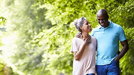 Couple walking together in a park with greenery in the background