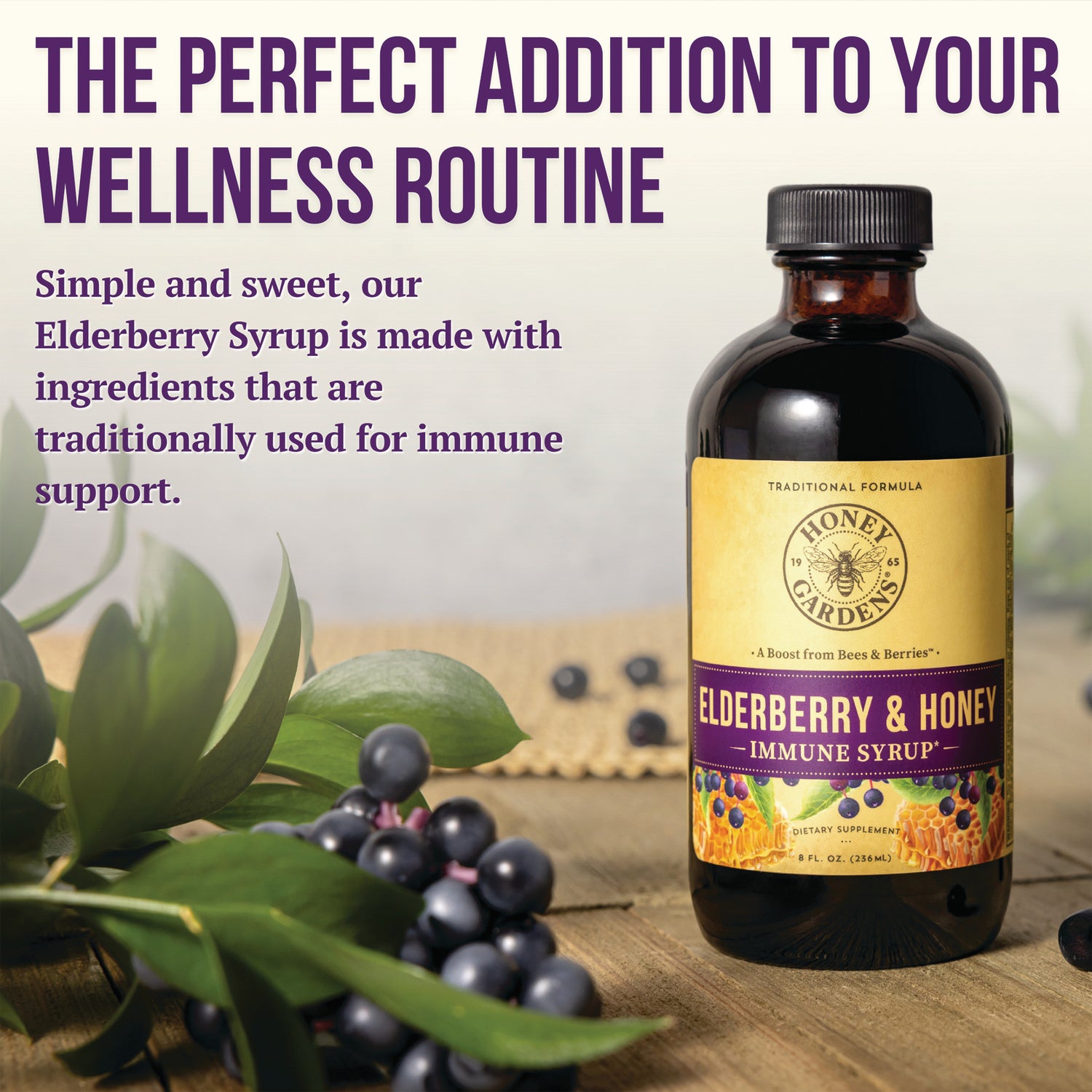 HGR004 | Elderberry & Honey immune syrup bottle with elderberries and leaves on a wood surface and headline The perfect addition to your wellness routine