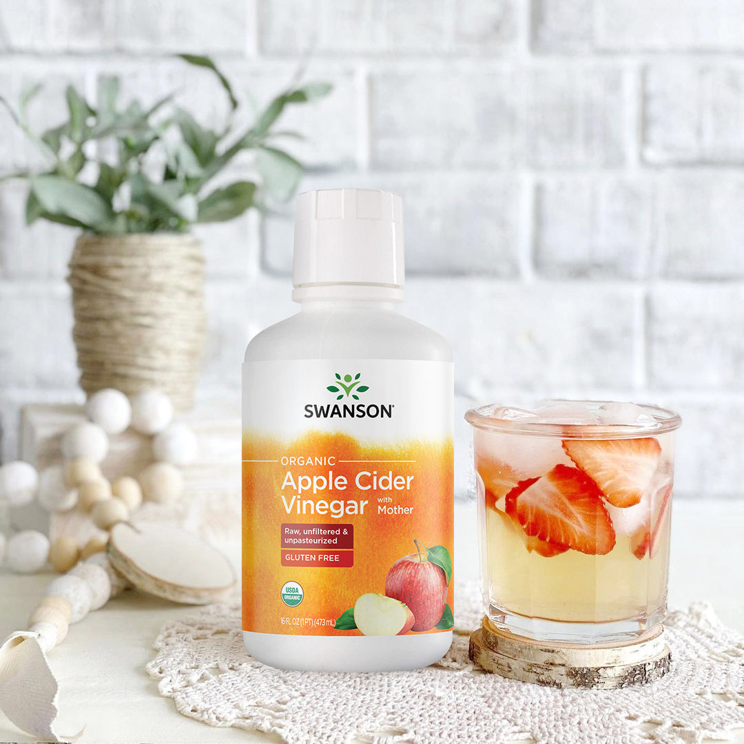 SWF195 | Swanson Organic Apple Cider Vinegar with Mother bottle beside iced drink with sliced strawberries