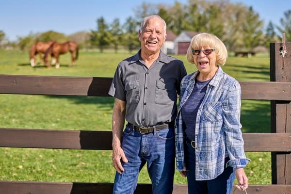 Man and women standing by a fence 